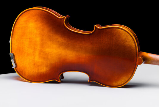 Violin body on its side as seen from the back on a white table isolated against a black backdrop