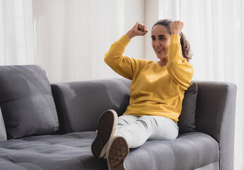 Portrait latin american woman one person smile enjoy sitting sofa and looking television raise your...