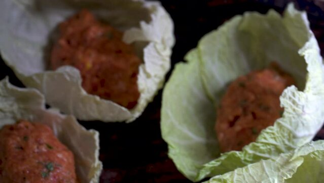 A person wraps balls of minced meat on cabbage leaves, spanish food, "puchero" balls.