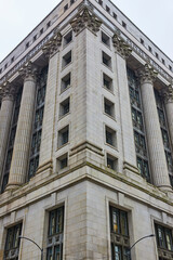 Obraz premium Corner of grey building with pillars and columns on overcast day with gloomy, ominous sky, Chicago