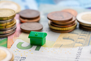 Small toy house by stacks of coins.