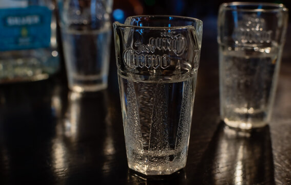 Traditional shot glasses for tequila close-up on blurred background of mexican tequila Olmeca Silver on dark table. Ukraine, Zhytomyr, December, 21, 2023