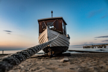 Boat on the Baltic Sea beach in the evening, focus on the rope