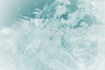 Bluewater waves on the surface ripples blurred. Defocus blurred transparent blue colored clear calm water surface texture with splash and bubbles. Water waves with shining pattern texture background.