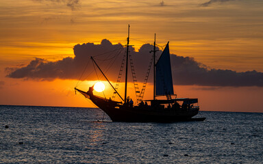 Silhouette of sailboat against a setting  sun in the Caribbean. 
