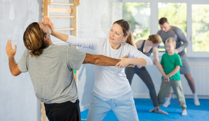 Man and woman at group self-defense lesson are learning new technique of blowing to chin, trainer...