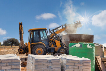 backhoe, on the construction site, loading a truck, cement in the front, african developments
