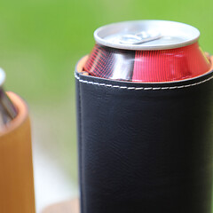 Leather drink holder in  black colors.  Grass background, Leather Drink Holder view. Leather Can Holder, leather beverage holder. outdoor shot. Space blank, Mockup.