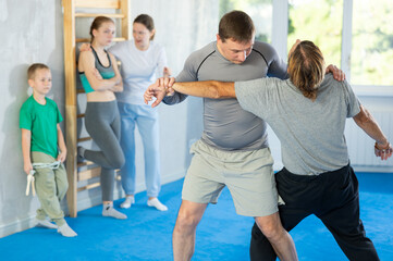 Man practices defensive movements by ptrip up with sparring partner during group training