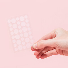 Woman holding pimple patch sheet on pink background  - obrazy, fototapety, plakaty
