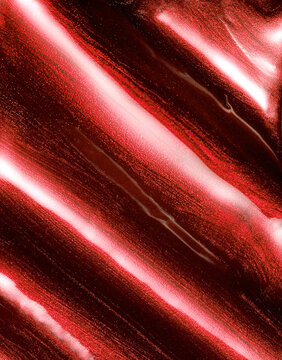 Red metallic shimmering glossy nail polish composition background. Cosmetic makeup product texture