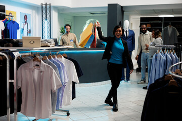 Happy asian woman laughing, holding shopping bags with purchased apparel in clothing store....