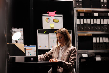 Investigator analyzing confidential case, checking crime scene evidence in arhive room. Caucasian...