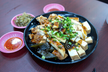 Chinese food, fried tofu with soy sauce on black plate on wooden table
