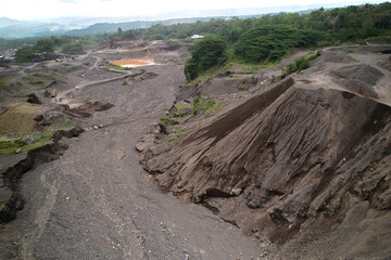 A stone quarry in Indonesia. Large equipment such as bulldozers and dump trucks are working on the site.