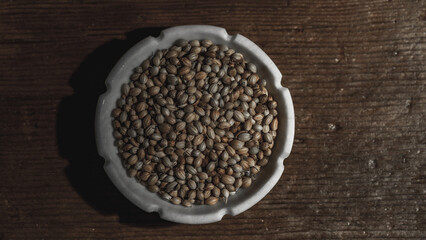 Coriander seeds in a bowl on wooden background. Close up.