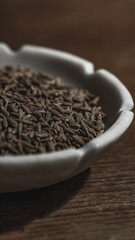 Cumin seeds in a bowl on wooden background. Close up.
