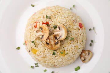 Delicious bulgur with vegetables, mushrooms and microgreens on plate, top view