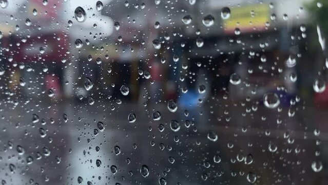 Water droplets and raindrops flowing on car glass, blur background of rain and road traffic, focus selected