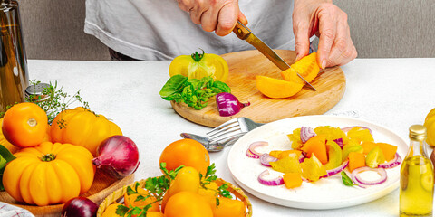 A woman is preparing a tomato salad. Ripe vegetables, herbs, aromatic spices, olive oil
