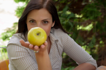 Attractive young woman holding yellow apple in the nature. Wanna bite?