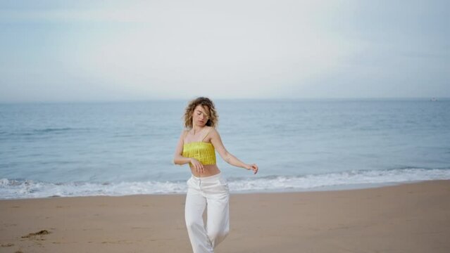 Girl choreographer moving body on ocean shore. Inspired female dancer performing