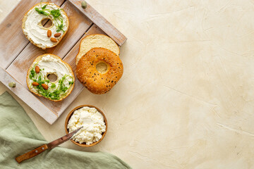Fresh baked bagels with cream on board, top view. Healthy breakfast background
