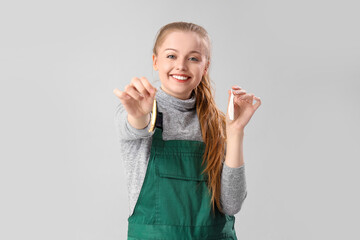 Happy young woman with fishing lures on light background