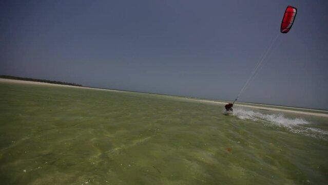 Epic panning shot of kite surfer in shallow ocean water