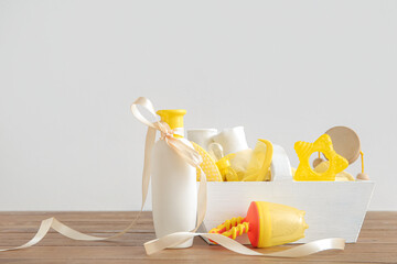 Basket with gifts for baby on brown wooden table near wall