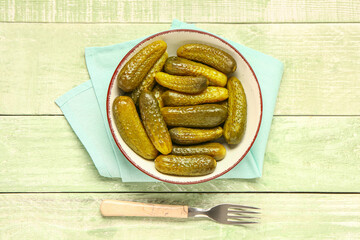 Bowl with tasty pickled cucumbers on green wooden background