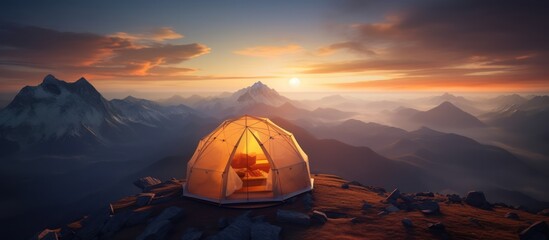 The dome tent is illuminated by the warm light of the rising sun as the golden cloudscape reveals dramatic mountain peaks from a panoramic landscape with blue, purple and orange skies