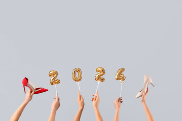 Female hands with shoes and figure 2024 on white background. New year shopping concept