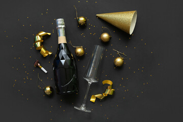 Bottle of champagne with glass and Christmas decor on black background