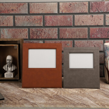 Leather photo frame in brown and gray colors.. Stone wall background, Creative composition of modern living room interior. Free space for text and picture or photograph . Stylish home accessor