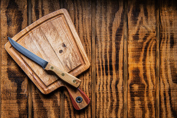 empty wooden cutting board and knife on wooden table. Preparation of appliances and ingredients for home cooking.