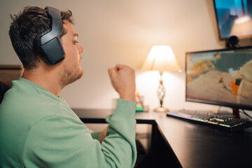 Gamer raising fist when win playing alone at home