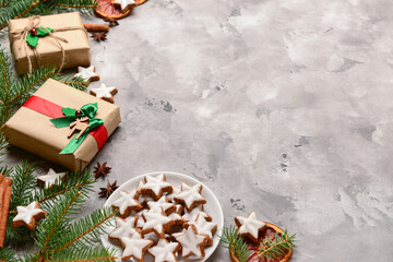 Delicious stars shaped Christmas cookies with fir branches and gifts on grey grunge background