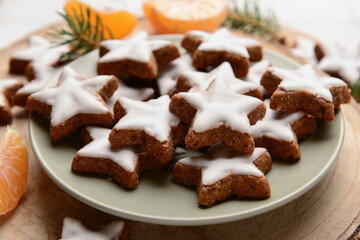 Fototapeta na wymiar Plate with delicious stars shaped Christmas cookies, fir branches and mandarin, closeup
