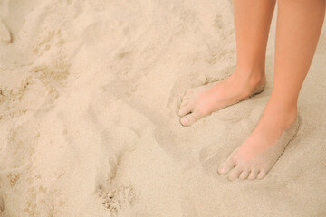 Fototapeta na wymiar Little girl standing on sandy beach, closeup. Space for text
