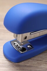One blue stapler on wooden table, closeup