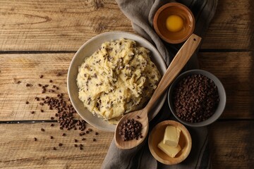 Chocolate chip cookie dough in bowl and ingredients on wooden table, flat lay
