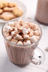 Cup of aromatic hot chocolate with marshmallows and cocoa powder on white table, closeup