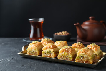Delicious fresh baklava with chopped nuts on dark textured table, closeup and space for text. Eastern sweets