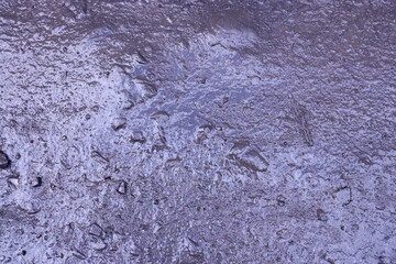 Close up of muddy puddle with small stones on wet surface. Background texture