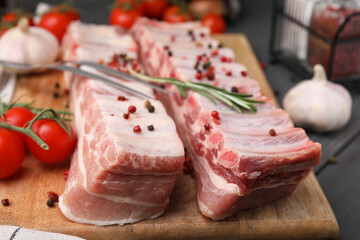 Raw pork ribs with peppercorns and rosemary on table, closeup