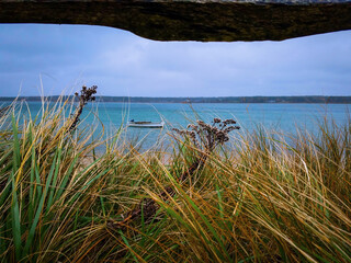 Oak Bluffs Martha’s Vineyard Seascape with seagrass on sand dune and a fishing boat on...