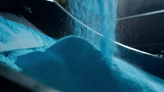 slow motion shot of blue polyethylene powder as it falls in the form of rain and forms a pile on a metal mold for rotomolding