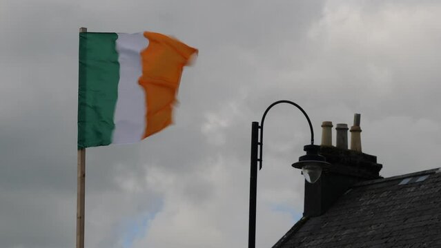 Swift Irish Flag Dance Amidst Cloudy Sky and Traditional Rooftop