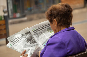 abuela leyendo diario en la plaza